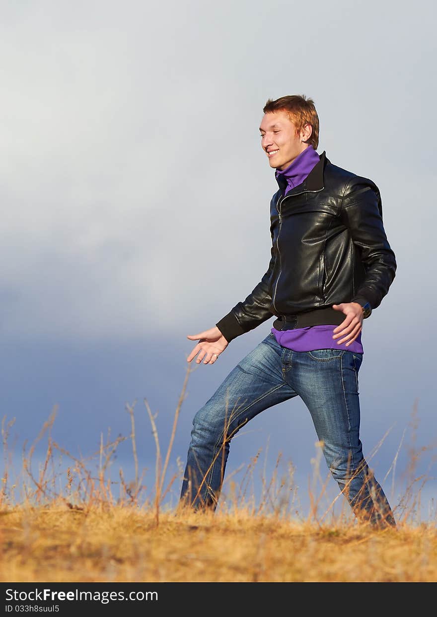 Happy young man in the field against clouds