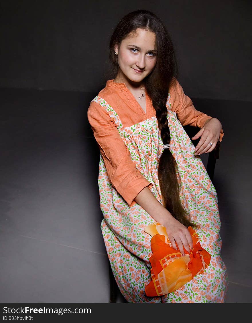 Portrait of a beautiful young girl with an enigmatic smile. Ethnic russian dress. Taken in a studio setting. Black background.