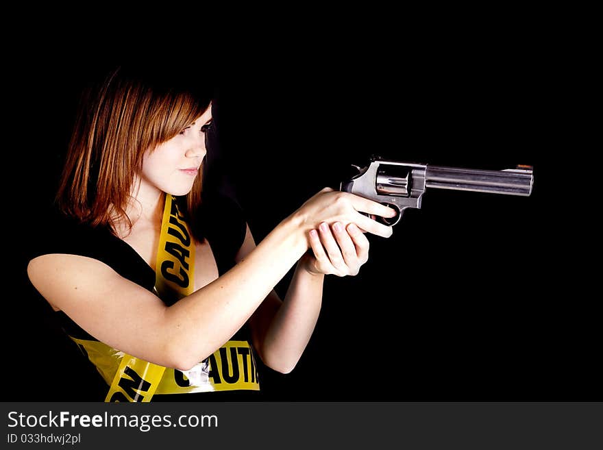 A woman pointing a gun while being wrapped up in caution tape. A woman pointing a gun while being wrapped up in caution tape.