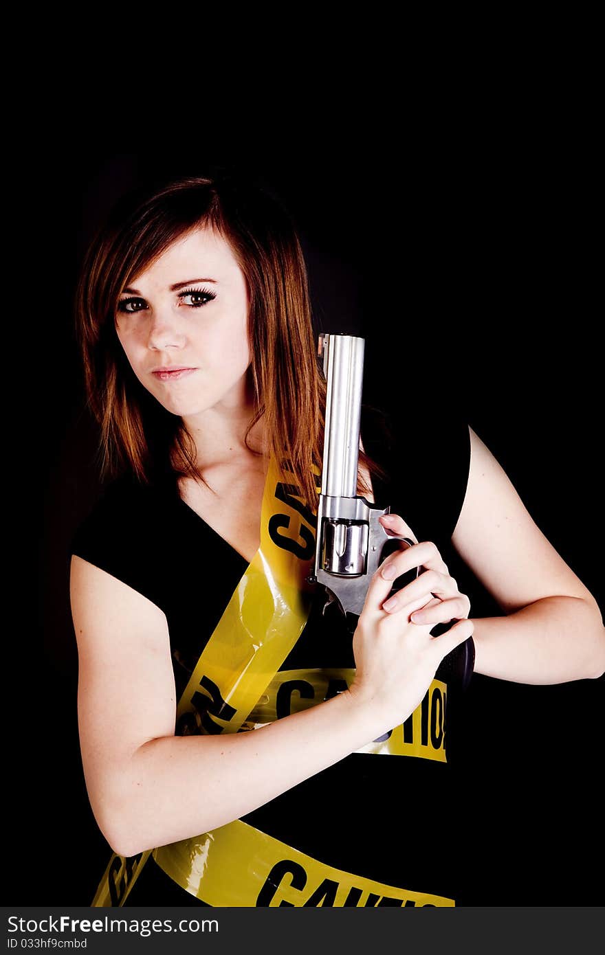 A woman holding a gun on a black background with caution tape wrapped around her. A woman holding a gun on a black background with caution tape wrapped around her.