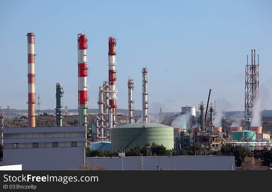 Towers and chimney in oil refinery over blue sky. Towers and chimney in oil refinery over blue sky
