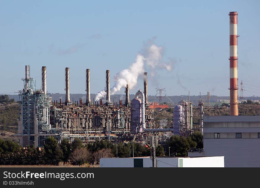 Towers and chimney in oil refinery over blue sky. Towers and chimney in oil refinery over blue sky