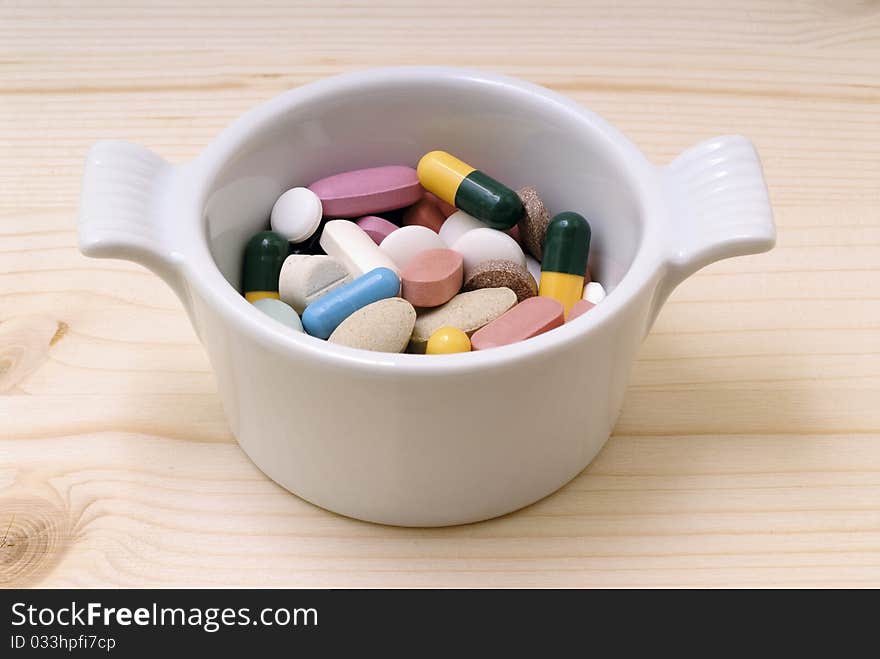 Saucepan with pills on a wooden board