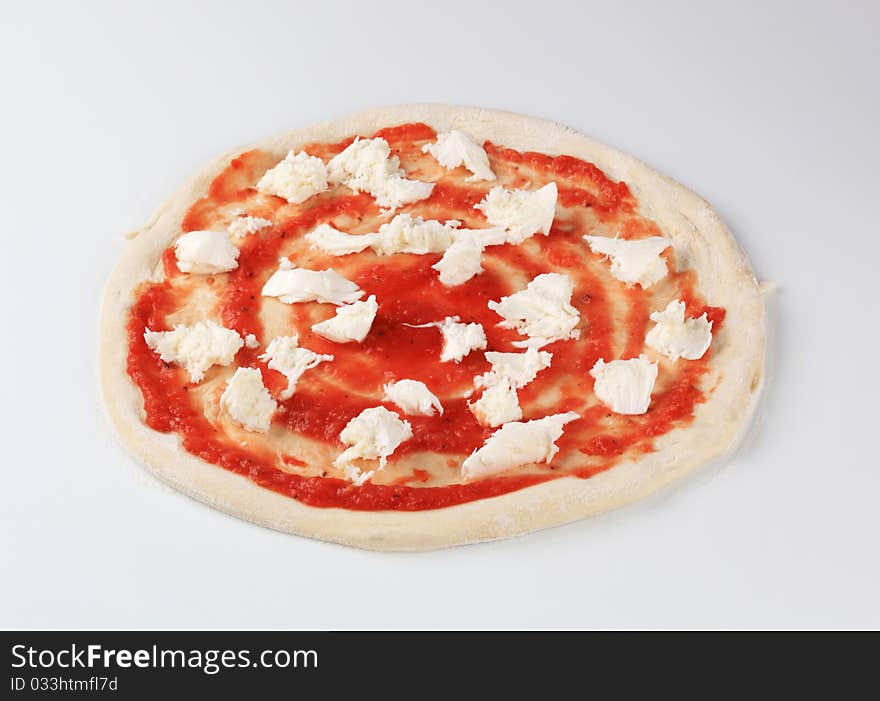 Tomato paste and mozzarella on raw pizza dough. Tomato paste and mozzarella on raw pizza dough