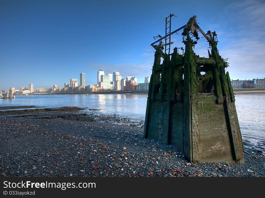 Low tide at the river Thames, Canary wharf business district skyline in a background, wide angle shot, subtle HDR. Low tide at the river Thames, Canary wharf business district skyline in a background, wide angle shot, subtle HDR