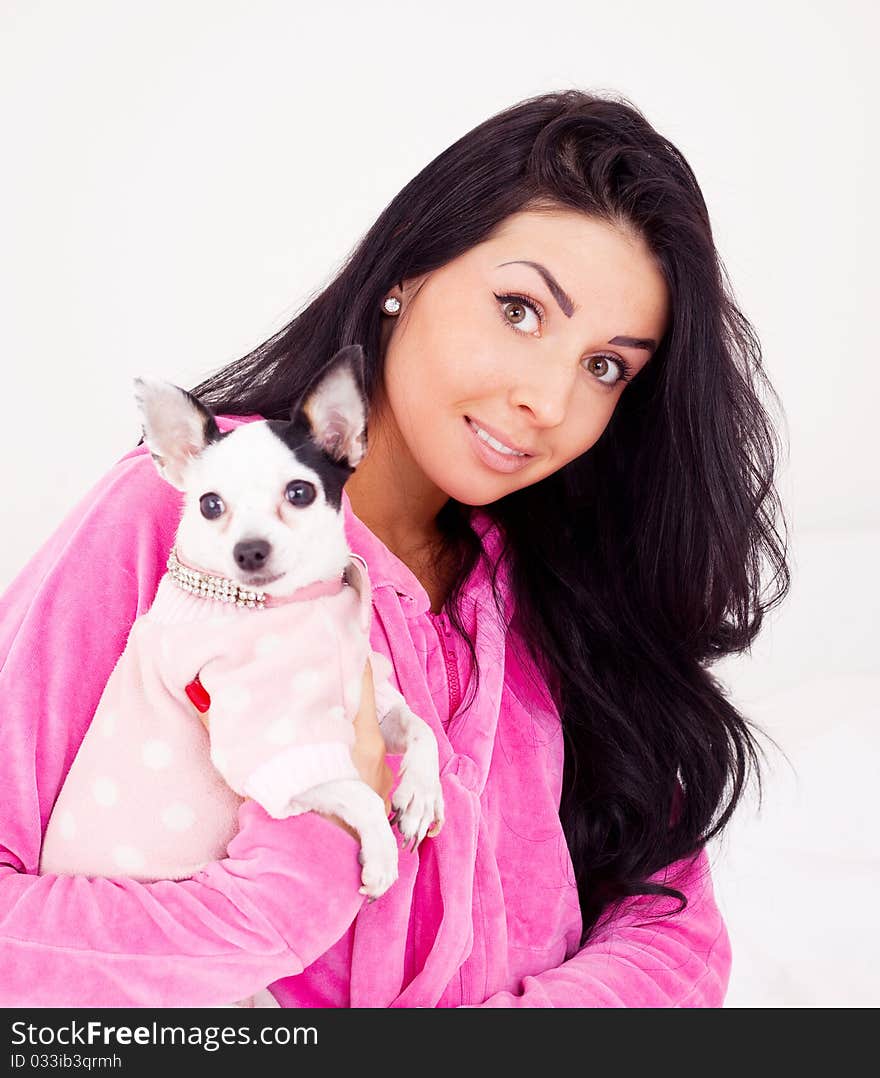 Beautiful young brunette woman with her dog on the bed