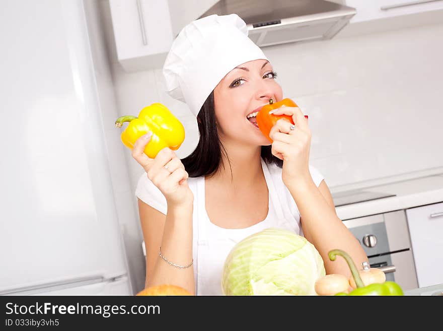 Beautiful young cook with vegetables in the kitchen