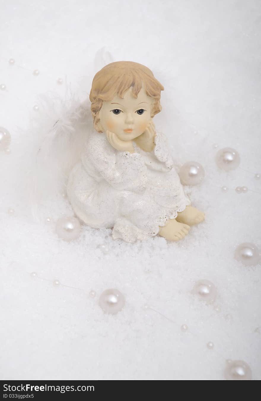 Christmas angel sitting in snow with white pearls. Christmas angel sitting in snow with white pearls