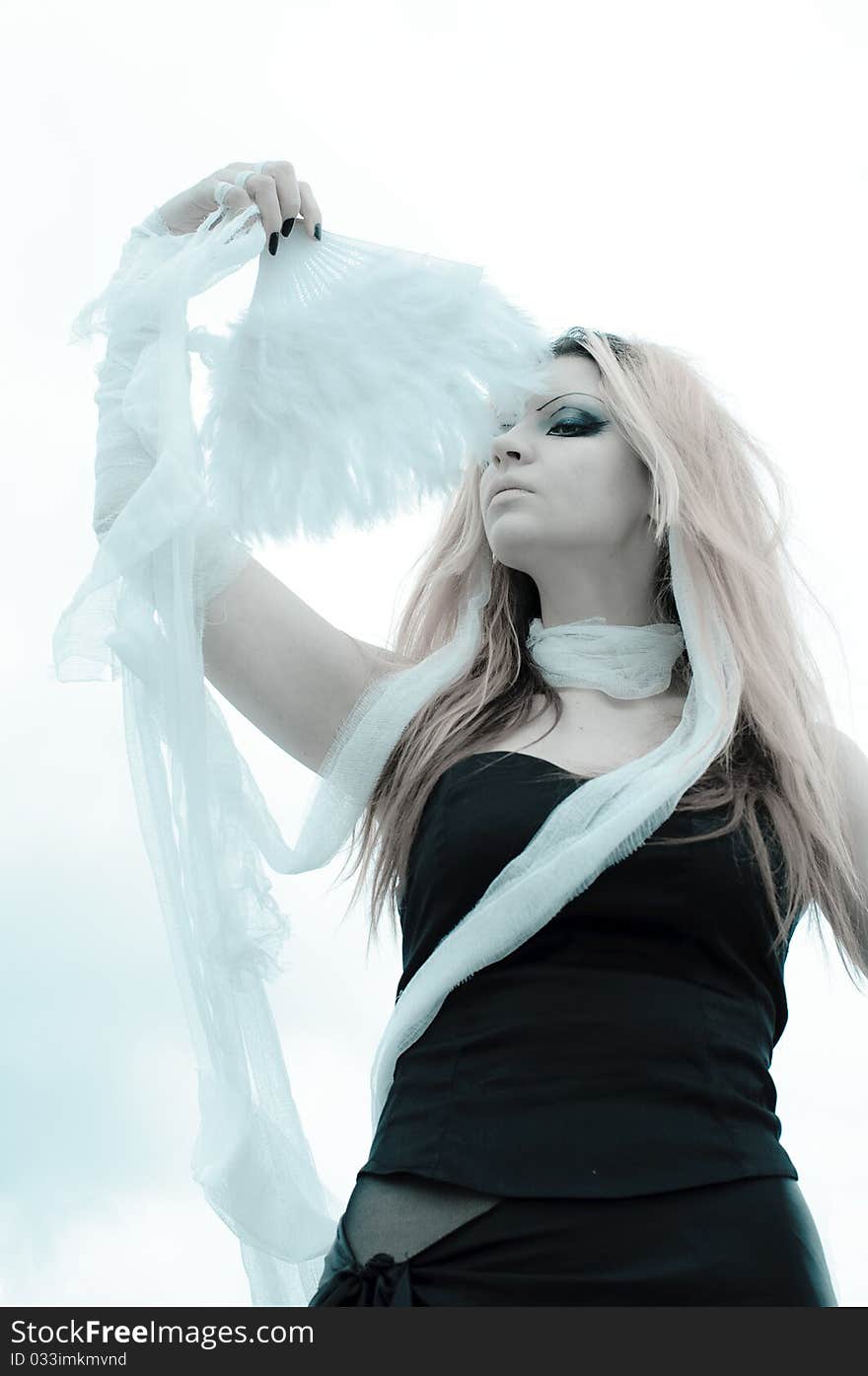 Photo of a Pretty red-haired girl with feathers, bandages and fan on rooftop