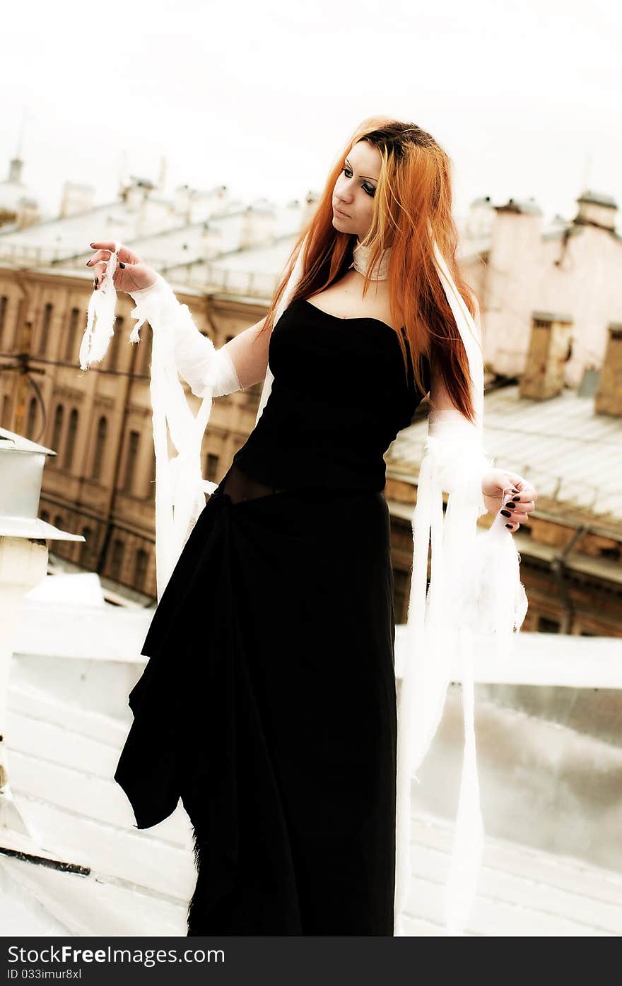 Photo of a Pretty red-haired girl with feathers, bandages and fan on rooftop