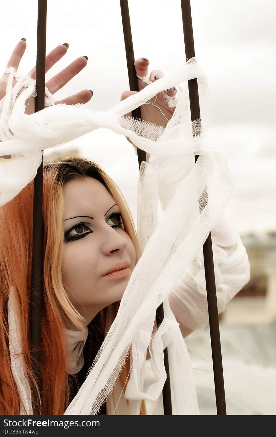 Photo of a Pretty red-haired girl with feathers, bandages and fan on rooftop