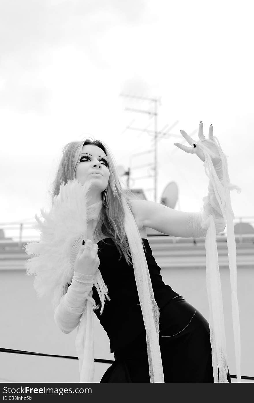 Photo of a Pretty red-haired girl with feathers, bandages and fan on rooftop