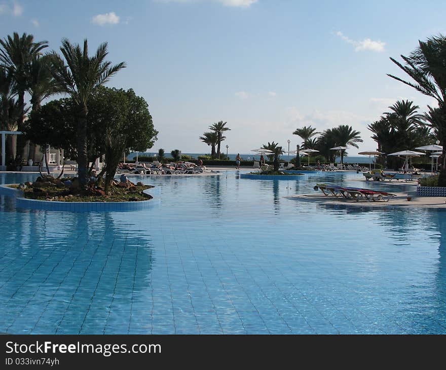 Swimming pool with palm trees on the background of the sea on the island Djerba, Tunisia. Swimming pool with palm trees on the background of the sea on the island Djerba, Tunisia