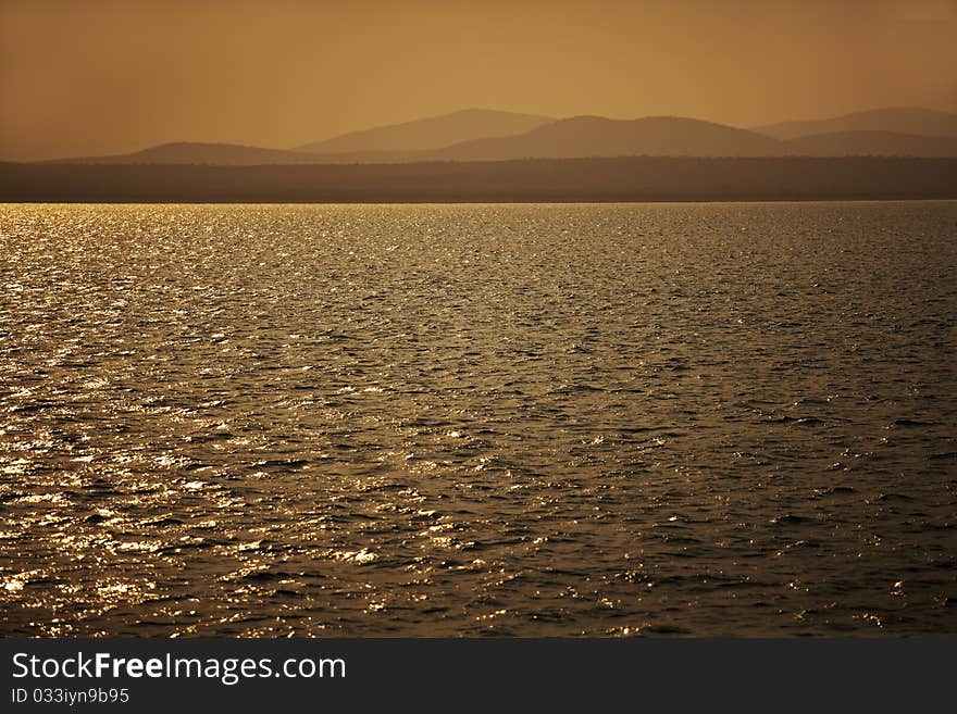 Sunset over a lake with misty hills. Sunset over a lake with misty hills