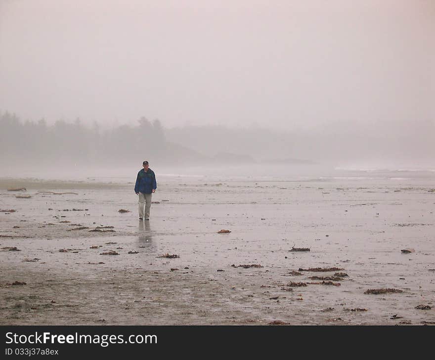 Man walking through the early morning mist on an ocean beach. Man walking through the early morning mist on an ocean beach