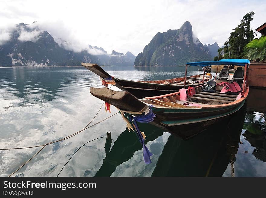 Long tailed boat floating on lake with limestone mountain.