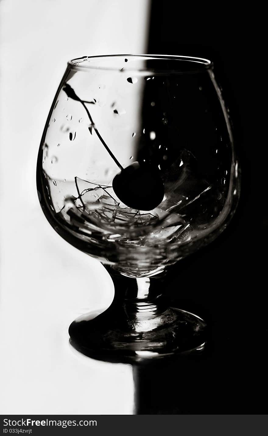 The Black-and-white image of a cherry in a glass with beaten glass