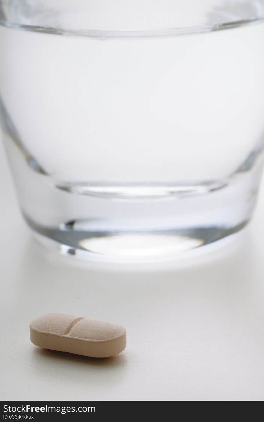 Pill next to a glass of water