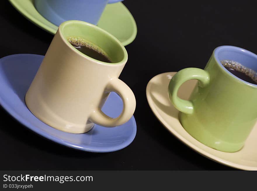 Three cups of espresso in yellow, green and blue cups