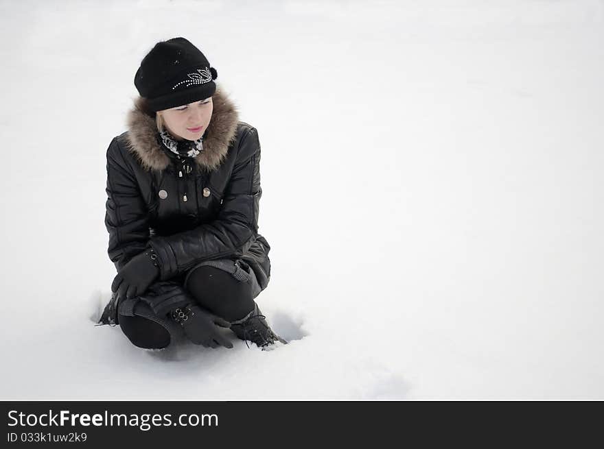 The girl in black clothes sits in white snow. The girl in black clothes sits in white snow