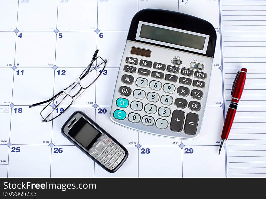 The calculator and mobile phone on a calendar. The calculator and mobile phone on a calendar