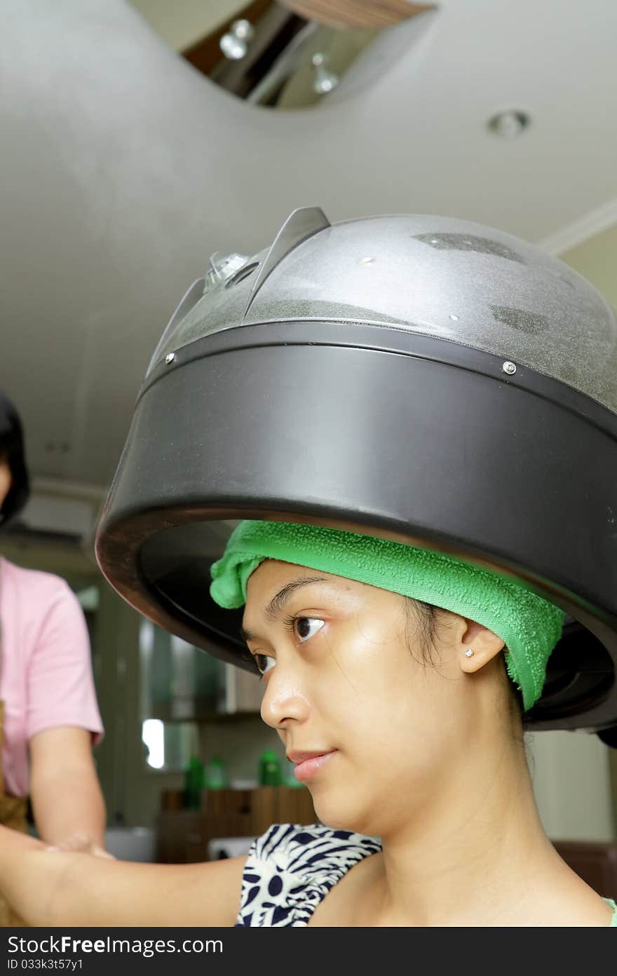 Asian ethnic young woman having hair steamed at hairdressing salon. Asian ethnic young woman having hair steamed at hairdressing salon