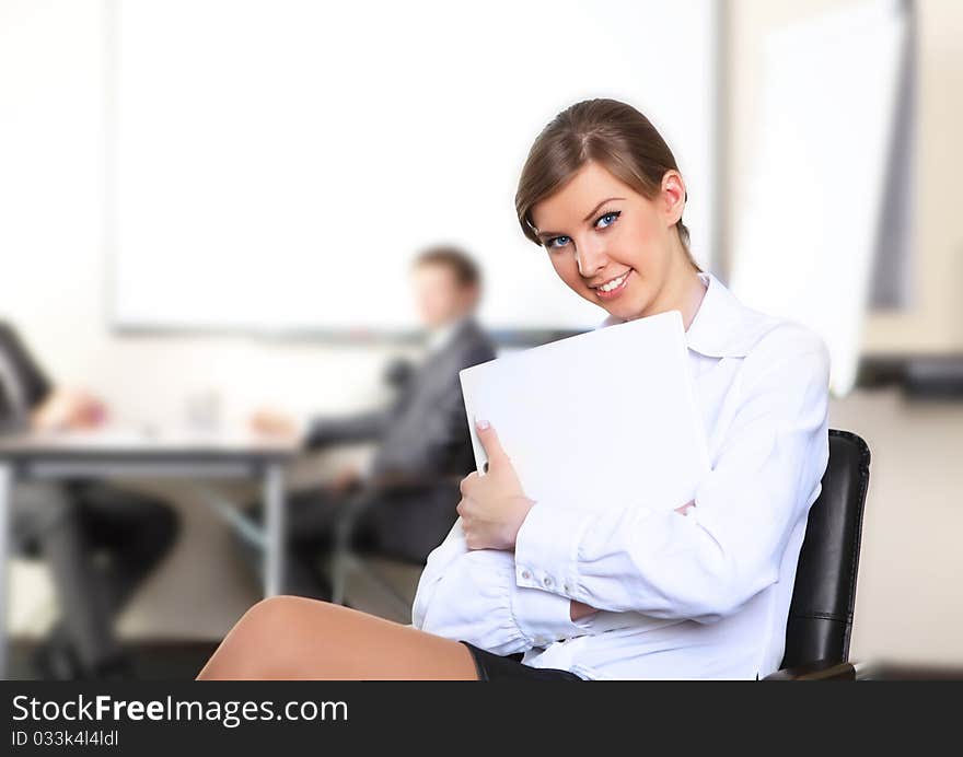 Portrait of a business girl sitting on a chair with a white folder in his hands.