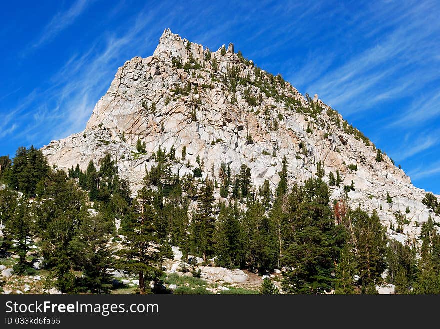 Mountain shooting up into a blue sky with wisps of clouds