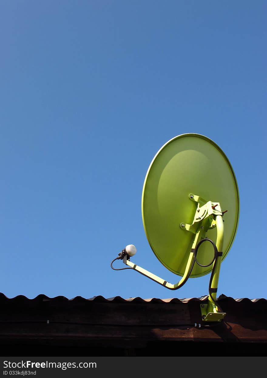 Green satellite dish on the roof with blue sky