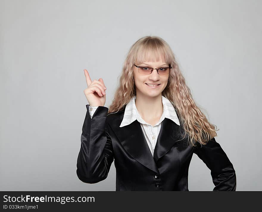 Funny business woman in a black suit with a gray background makes various hand gestures