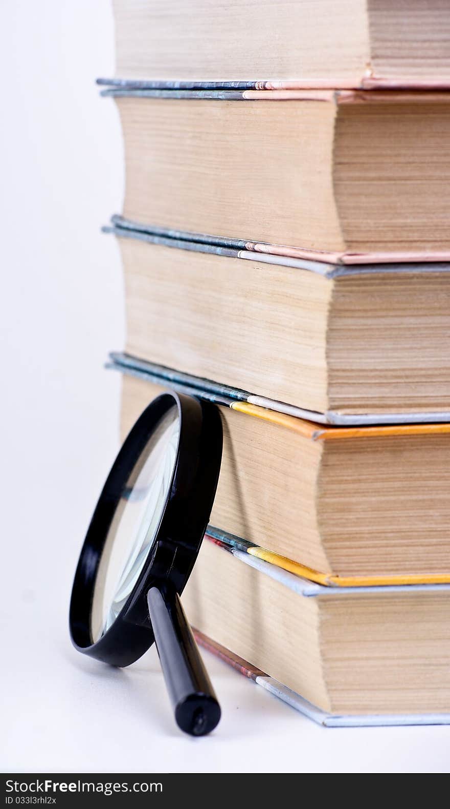 Books and magnifying glass on white background