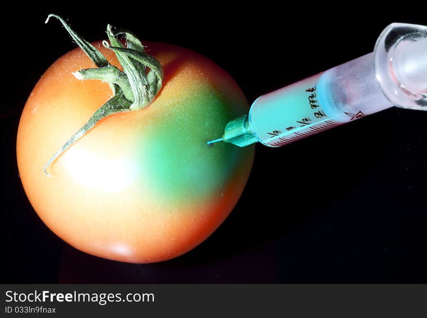 Injecting some liquid in a red tomato with a cristal syringe. Injecting some liquid in a red tomato with a cristal syringe.