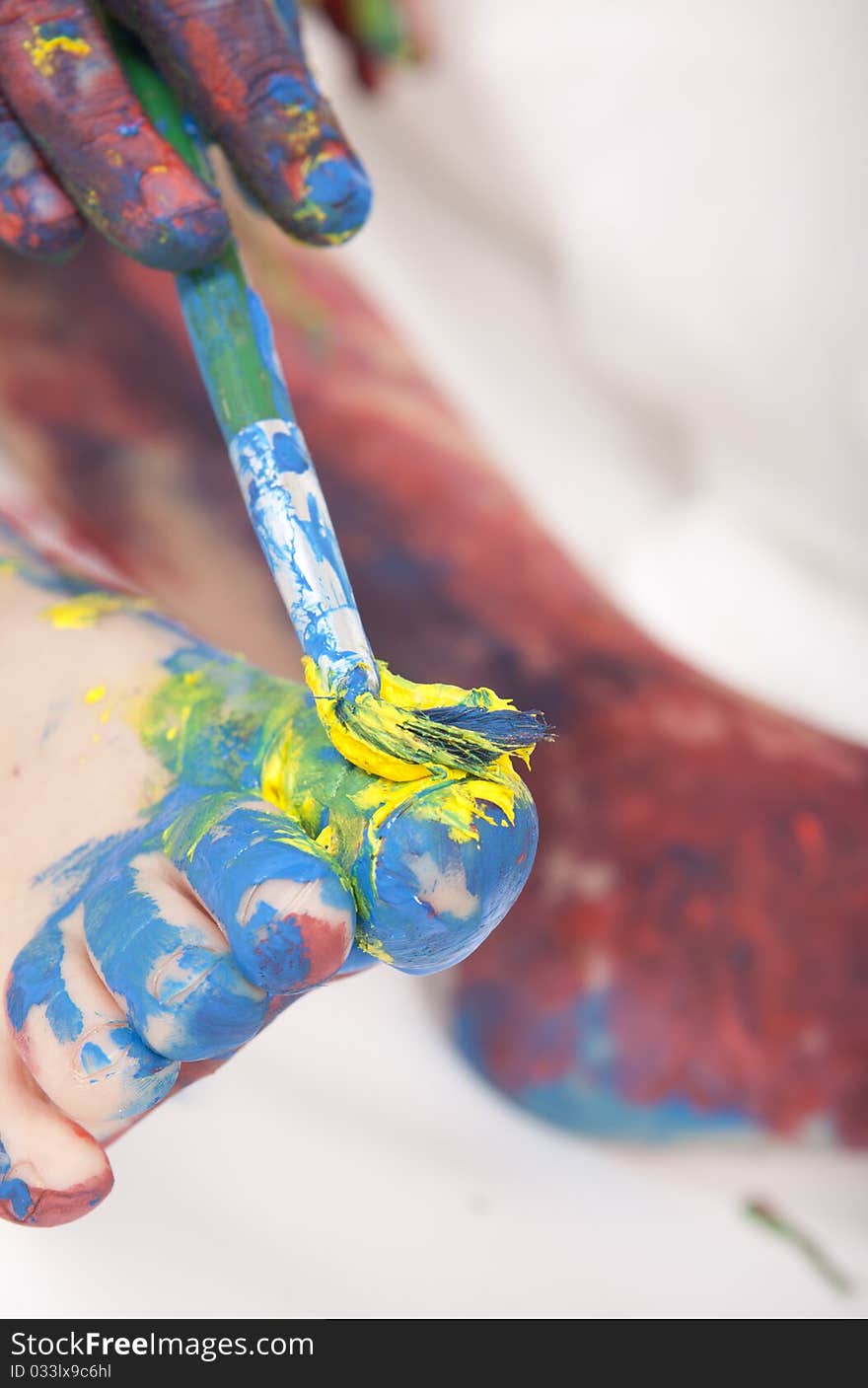 Beautiful baby covered in bright paint with paint brush. Beautiful baby covered in bright paint with paint brush