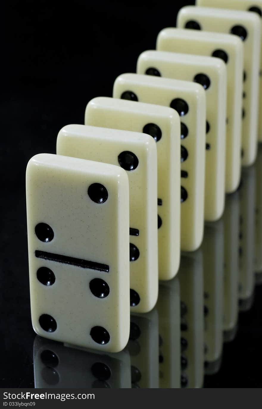 Dominoes waiting to fall,  white tiles on black background. Dominoes waiting to fall,  white tiles on black background.