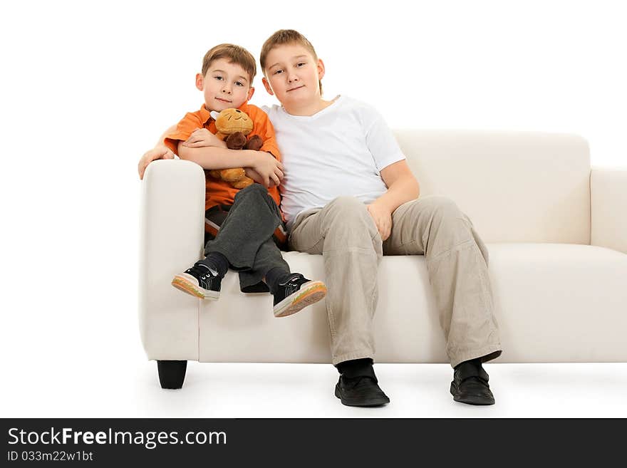 Two brothers sitting on a sofa on a white background