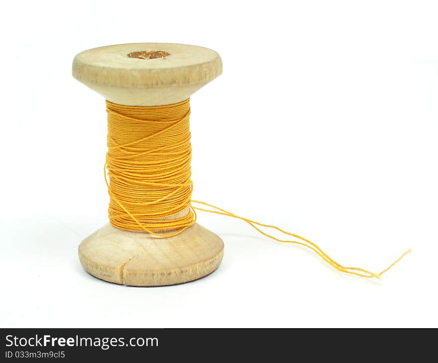 The spool of yellow threads on a white background