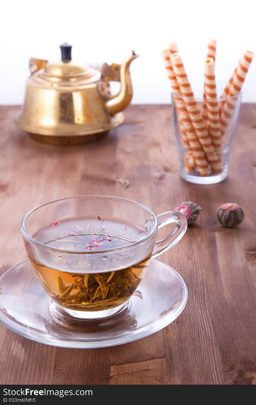 Transparent cup of green tea with old teapot and wafers