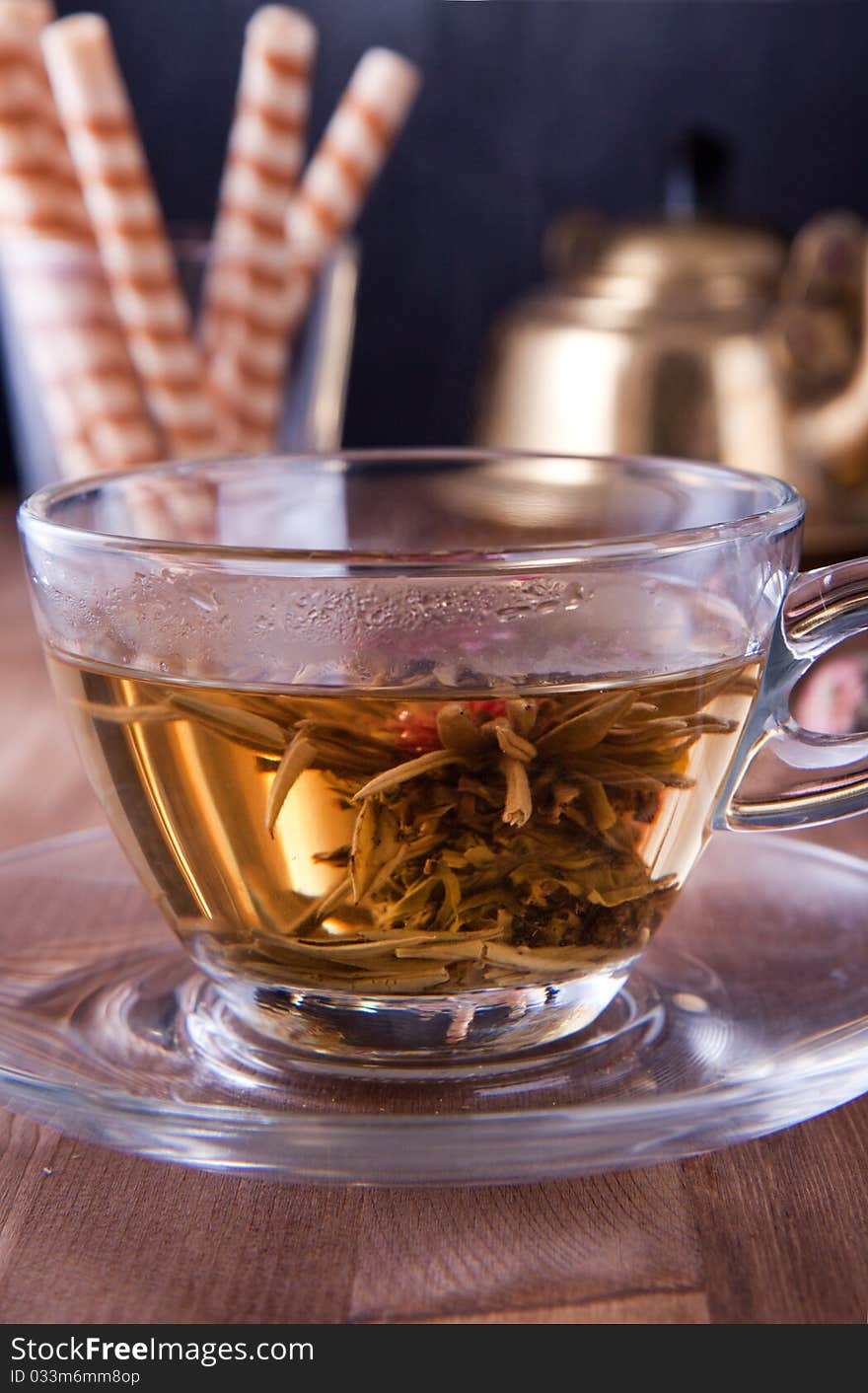 Transparent cup of green tea with old teapot and wafers