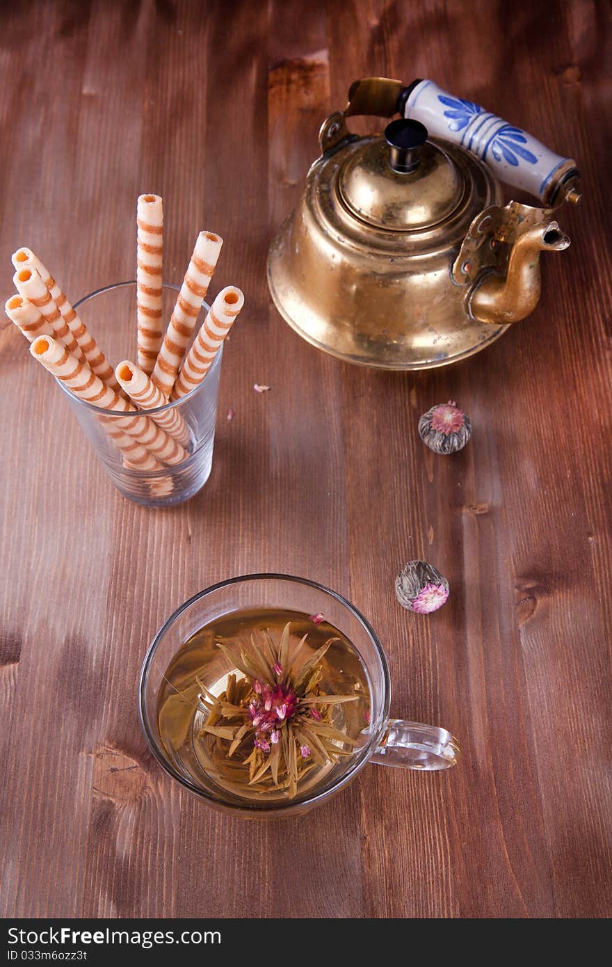 Transparent cup of green tea with old teapot and wafers