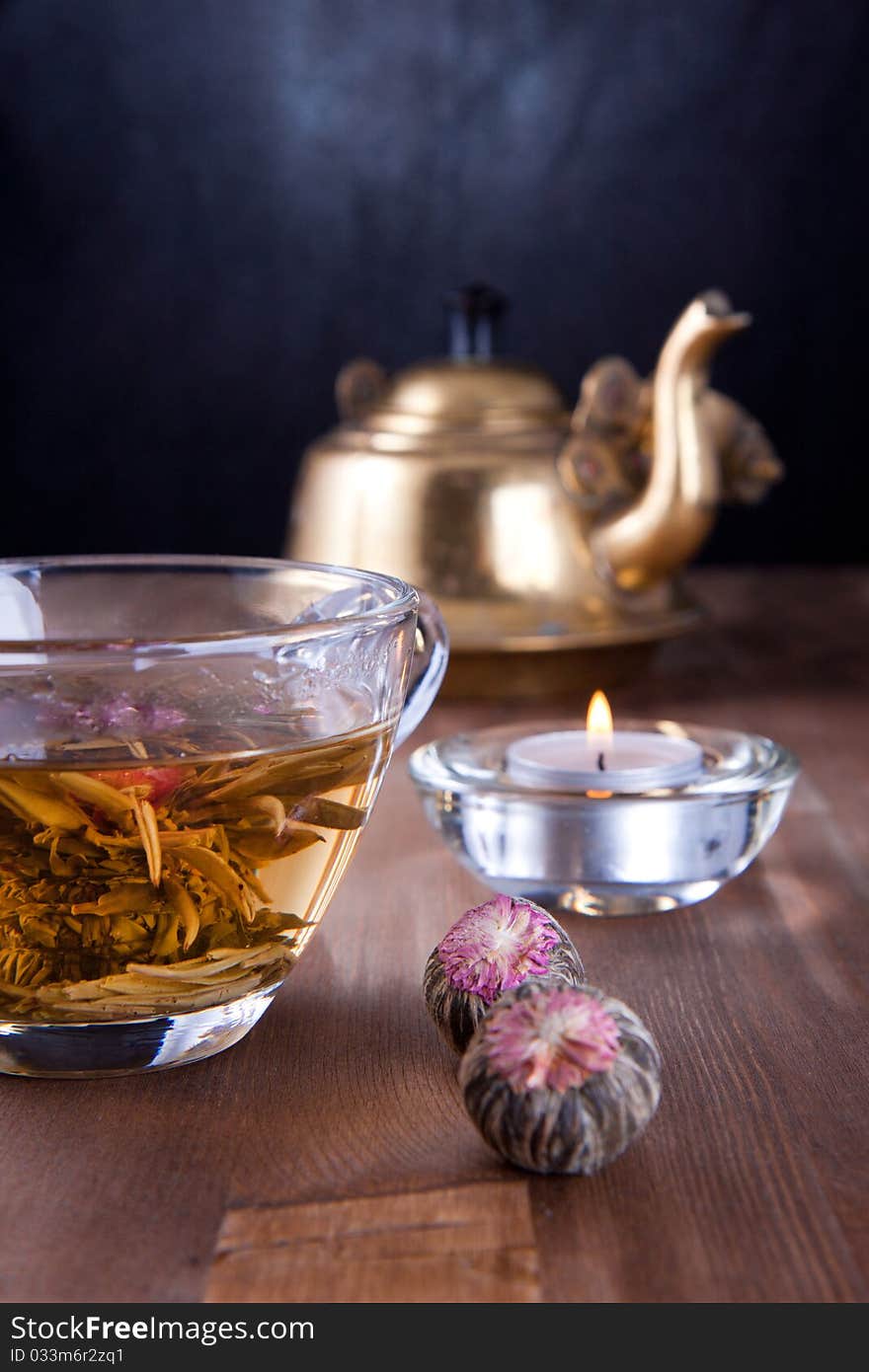 Transparent cup of green tea, burning candle and old teapot