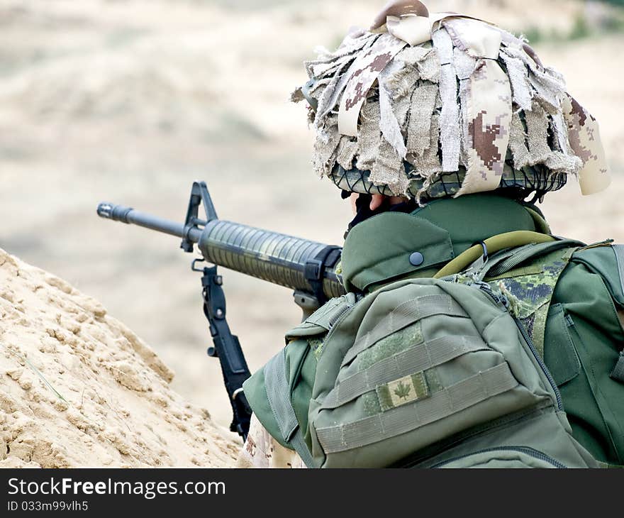 Soldier in desert uniform aiming his rifle