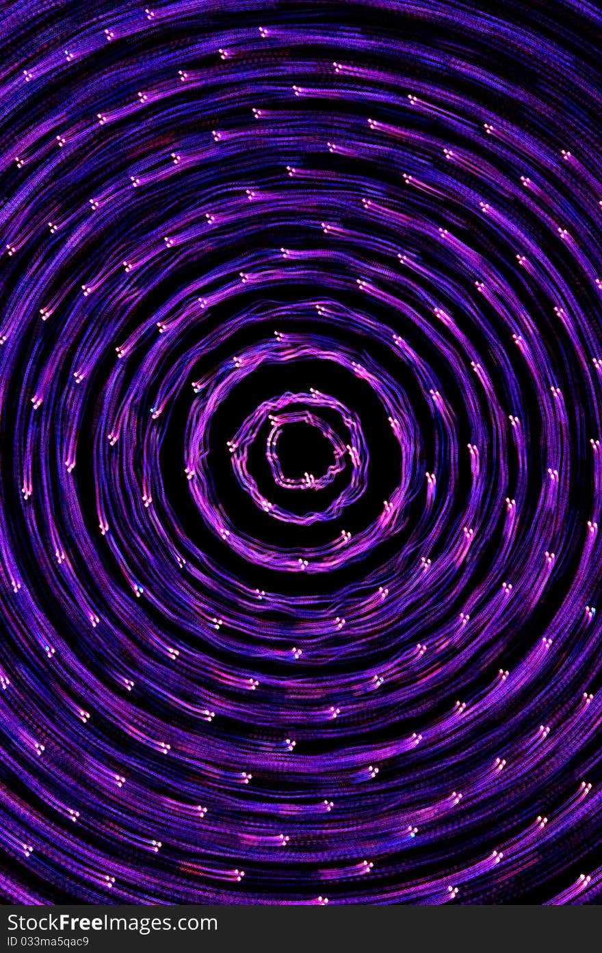 Purple points of light swirl around the center of this vertical image. Purple points of light swirl around the center of this vertical image