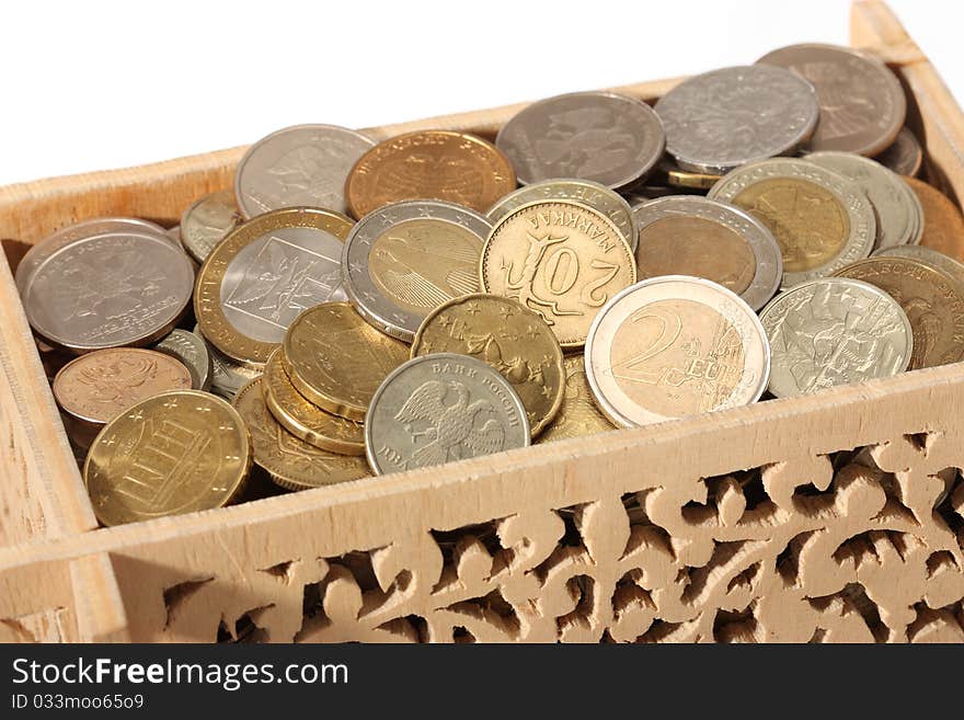 Close-up of carved wooden box filled with coins isolated on white