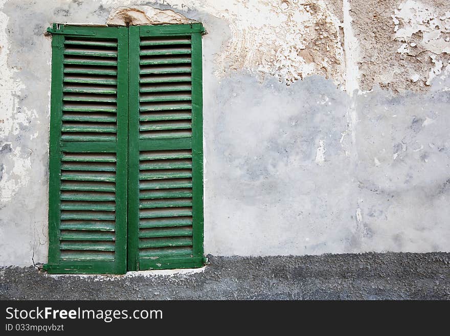 Old-fashioned window with green closed shutters (traditional building in a town on Majorca island in Spain)