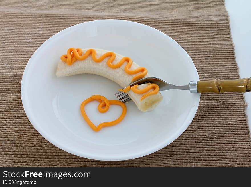 Banana with easy spread cheese and fork on white plate. Banana with easy spread cheese and fork on white plate.