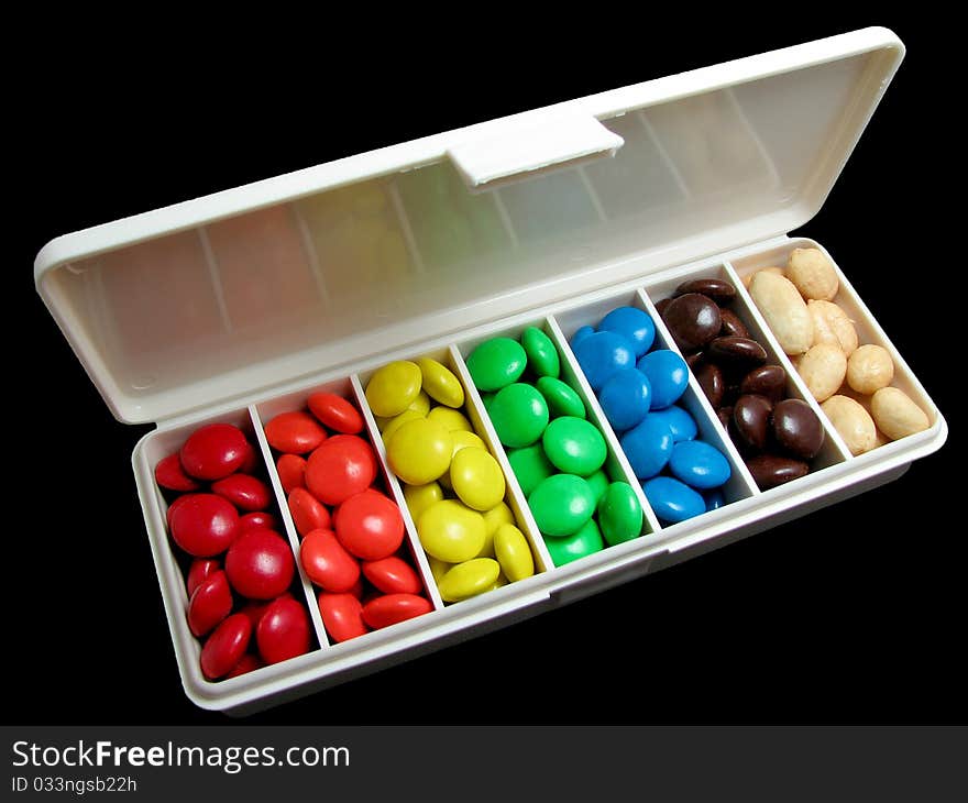 Pillbox filled with colorful candy and peanuts; black background. Pillbox filled with colorful candy and peanuts; black background.