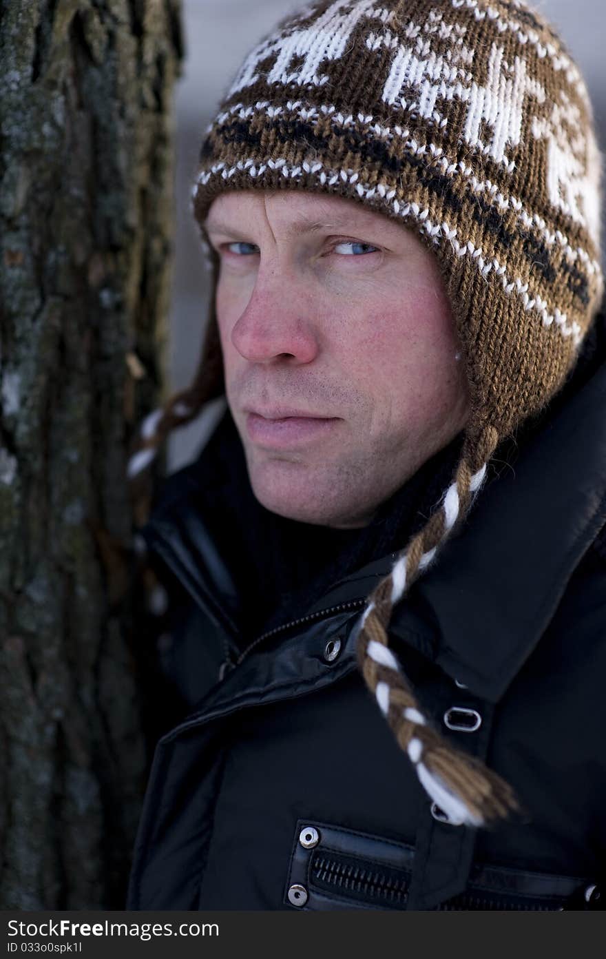 Man in winter leaning on tree