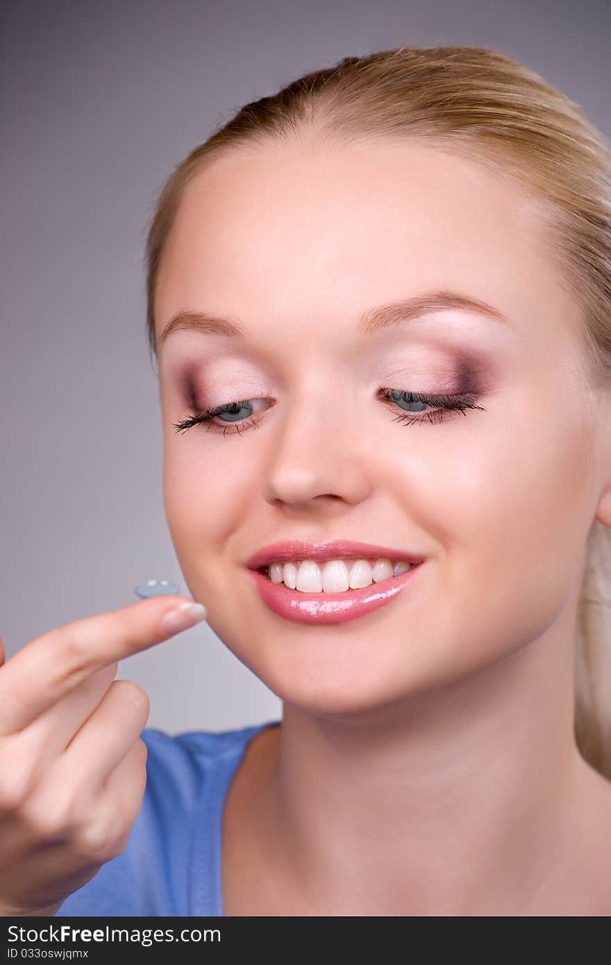 Contact lens on finger of young woman, close-up portrait