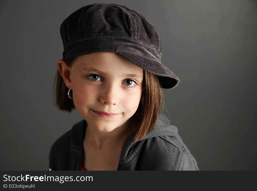 Close up of a beautiful young female child wearing a newsboy cap and hoop earrings. Close up of a beautiful young female child wearing a newsboy cap and hoop earrings