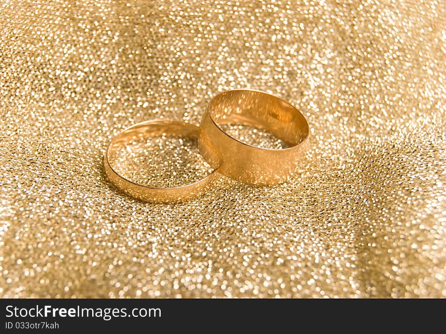 Gold wedding rings on a golden fabric background. Gold wedding rings on a golden fabric background